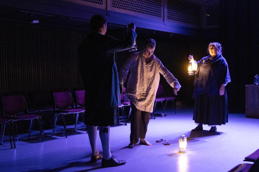 En full sjømann sliter med å kle på seg, mens en adelsmann står til venstre for ham og en adelskvinne står til høyre for ham og ser på, misfornøyde.