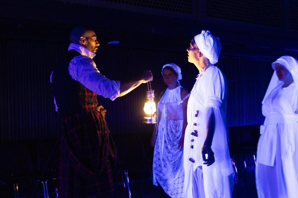 Macbeth med lykt, konfrontert av tre hekser.