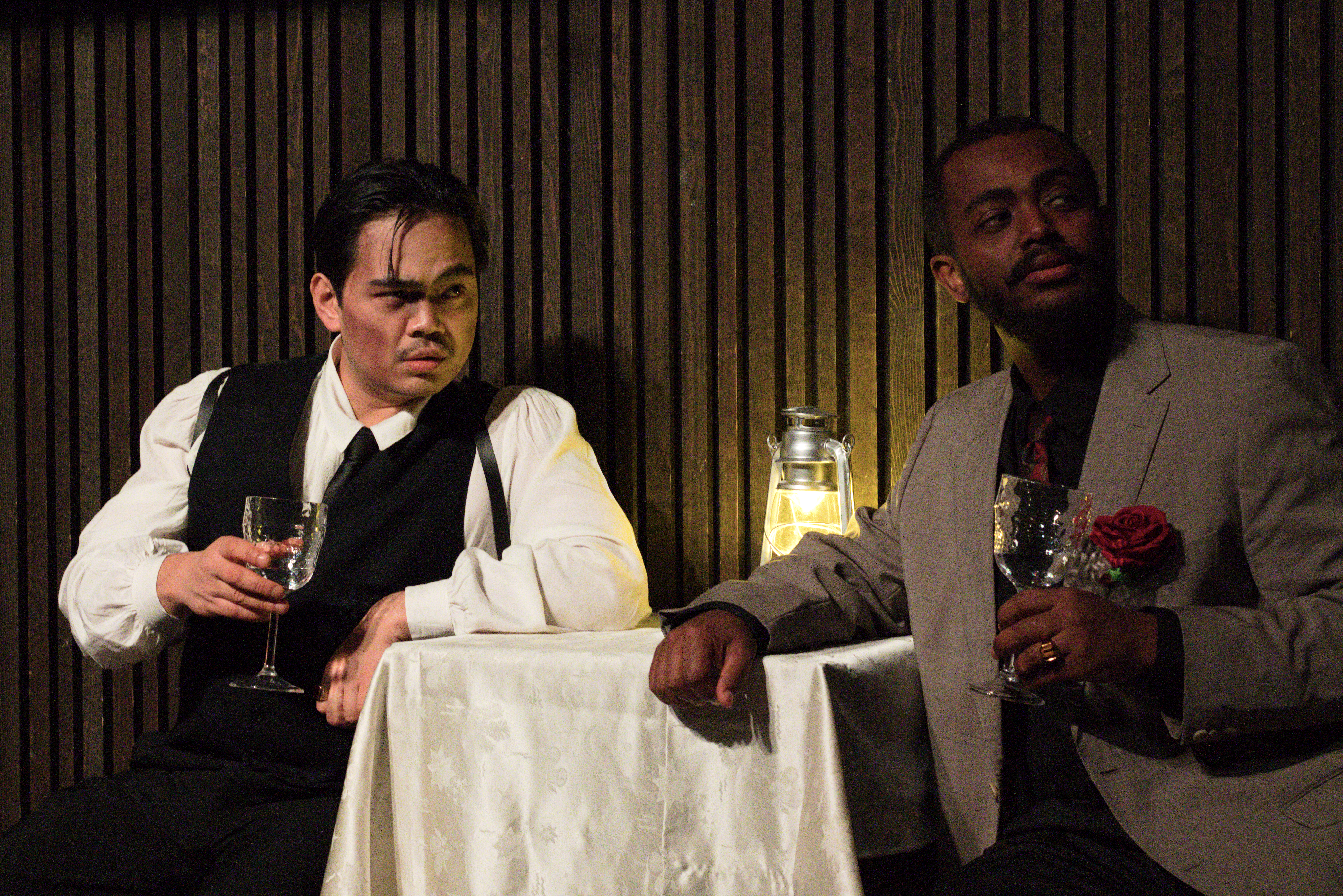 To gangstere, i dress, som sitter ved et bord og drikker vin.