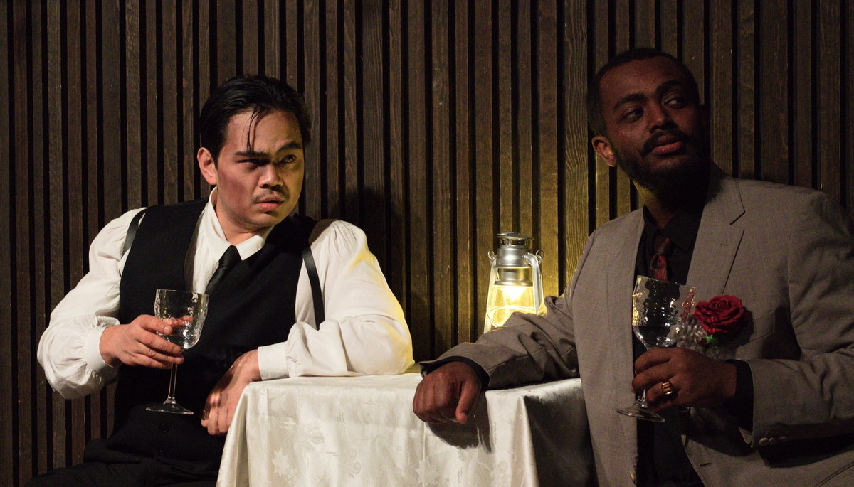 To gangstere, i dress, som sitter ved et bord og drikker vin.