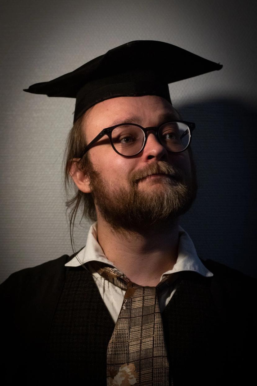 Professor med studenthatt, briller og generell tweed-vibe.