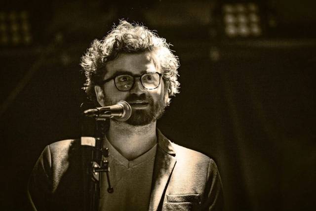 Svart/hvitt-bilde av Johannes foran mikrofon.