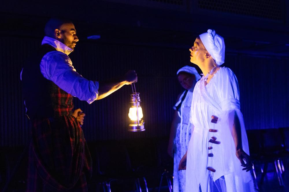 Macbeth med lykt, konfrontert av to av heksene.