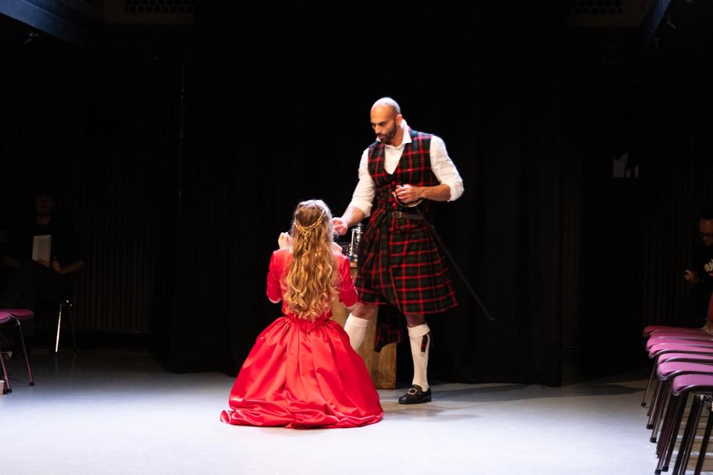 Lady Macbeth kneler på gulvet. Macbeth snakker til henne.