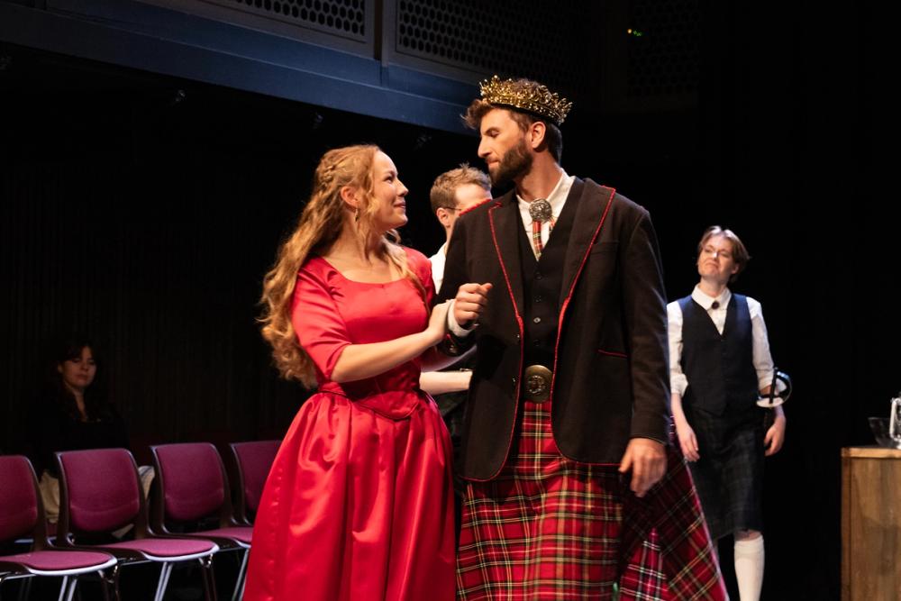 Lady Macbeth holder tak i armen til kong Duncan og snakker til ham.