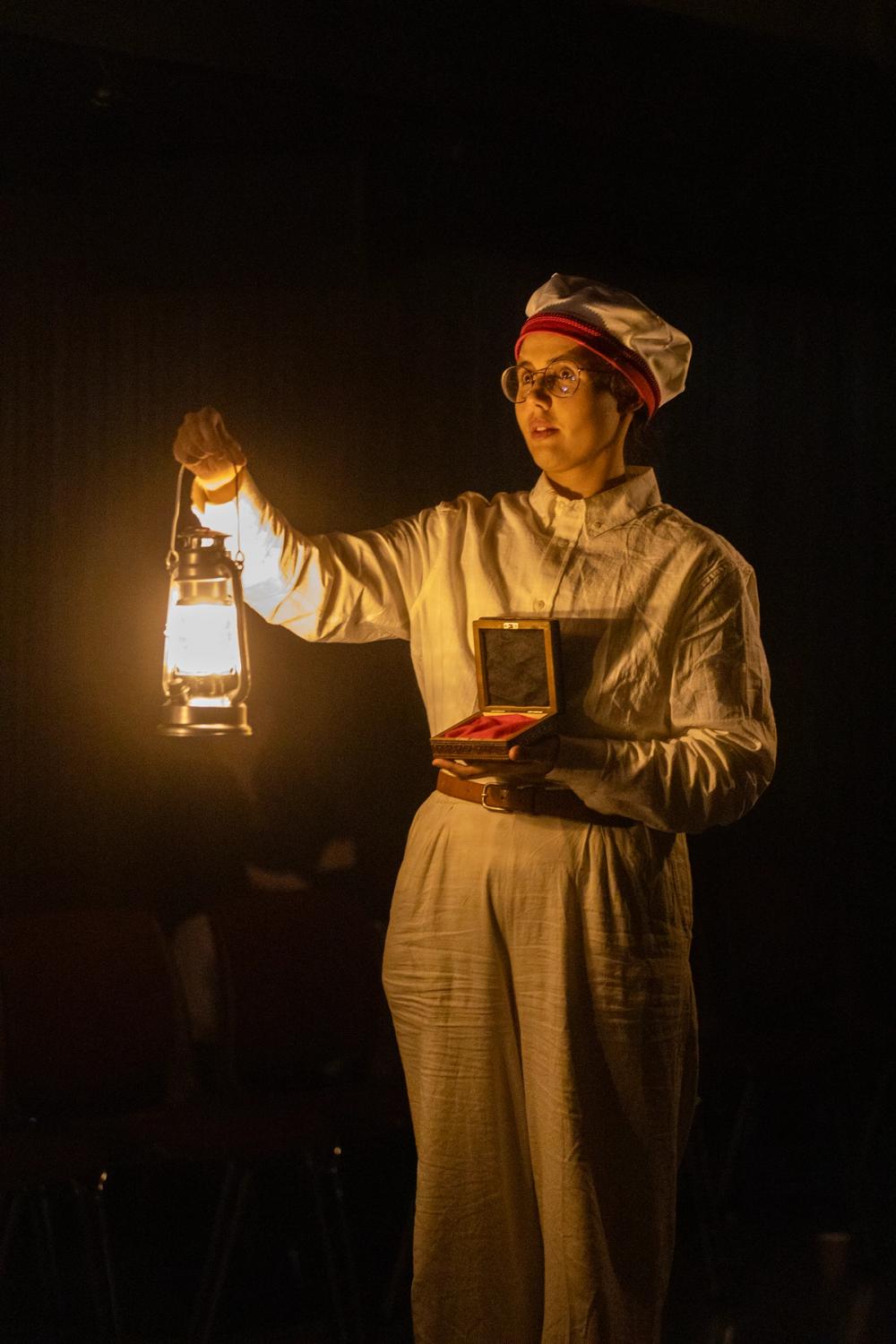 En matros med en boks medaljer og lykt i mørket.