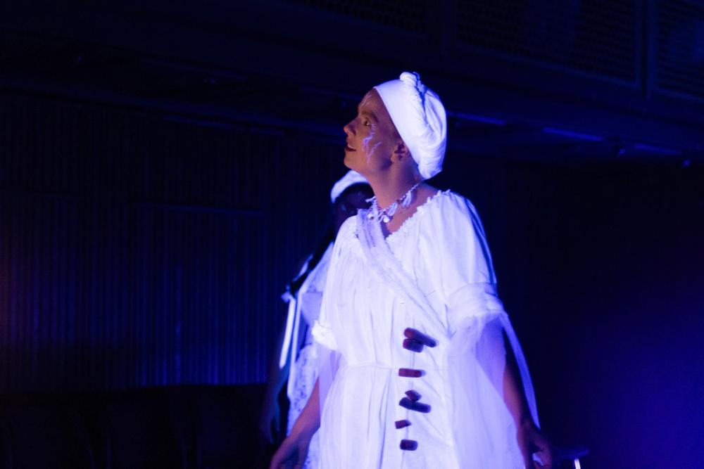 Heks som lyser i mørket, ansiktet svakt lyst opp av en lykt, og blodårer gløder blått i ansiktet hennes.