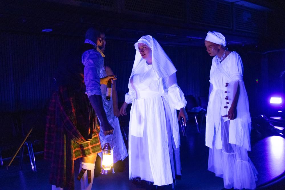 Macbeth som trekker seg bakover mens heksene går mot ham.