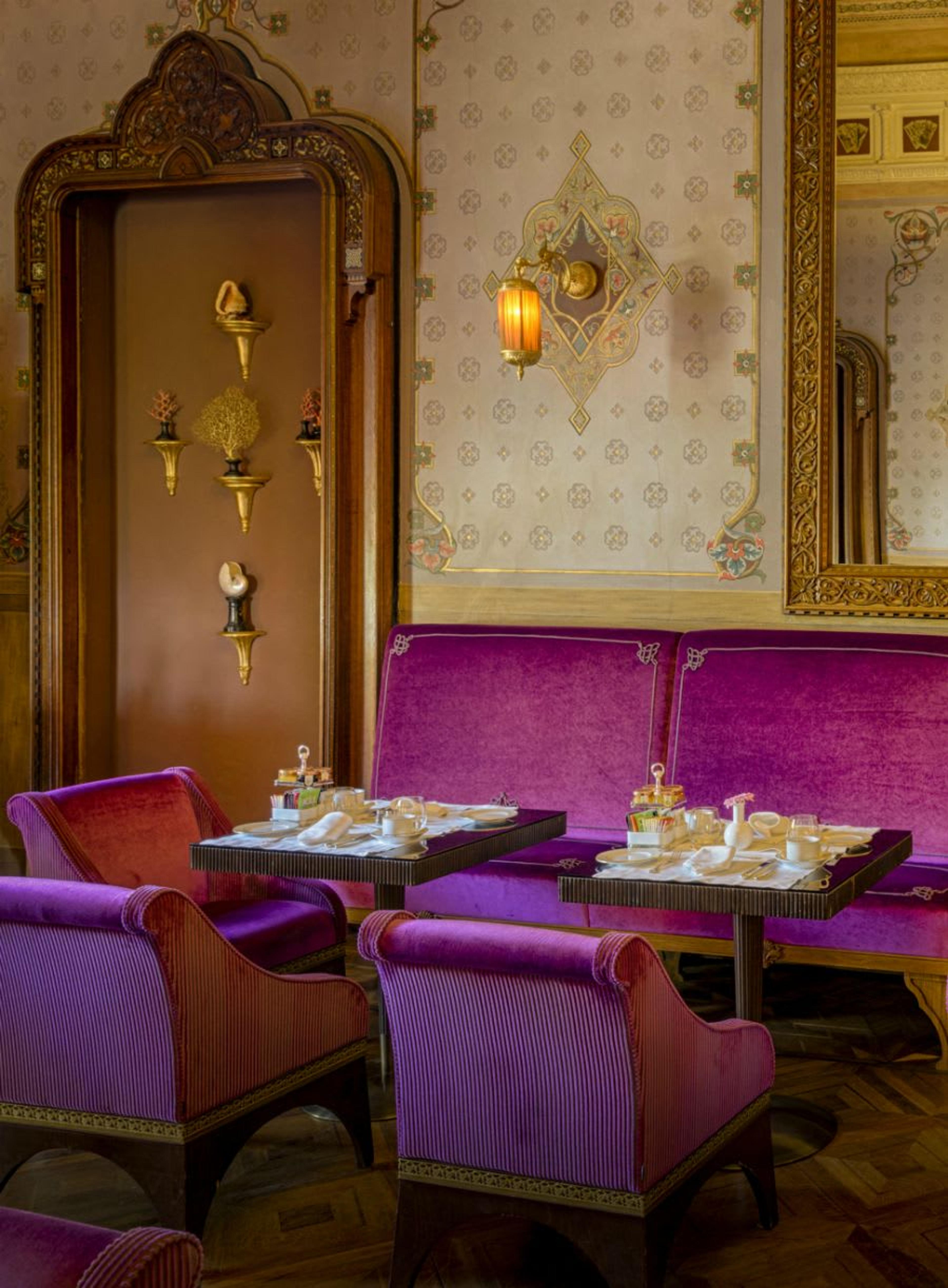 Frühstück im Kartenzimmer der Villa - lilafarbene Samtstühle, zarte goldene Fresken, Parkettboden und handgeschnitzte, holzgerahmte Spiegel an den Wänden.