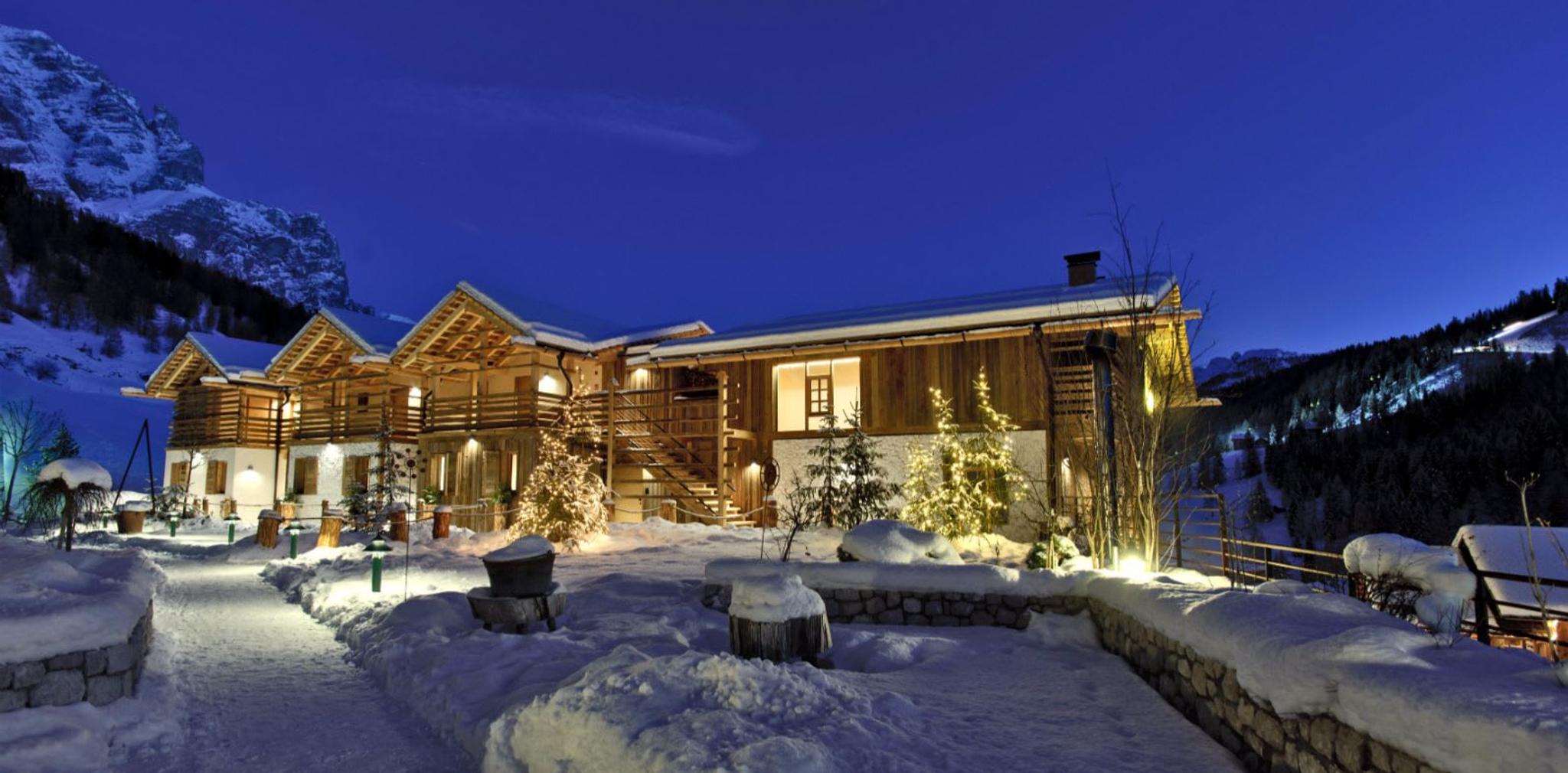 Vue romantique des cinq chalets de l'hôtel Fanes, recouverts d'une douce neige.