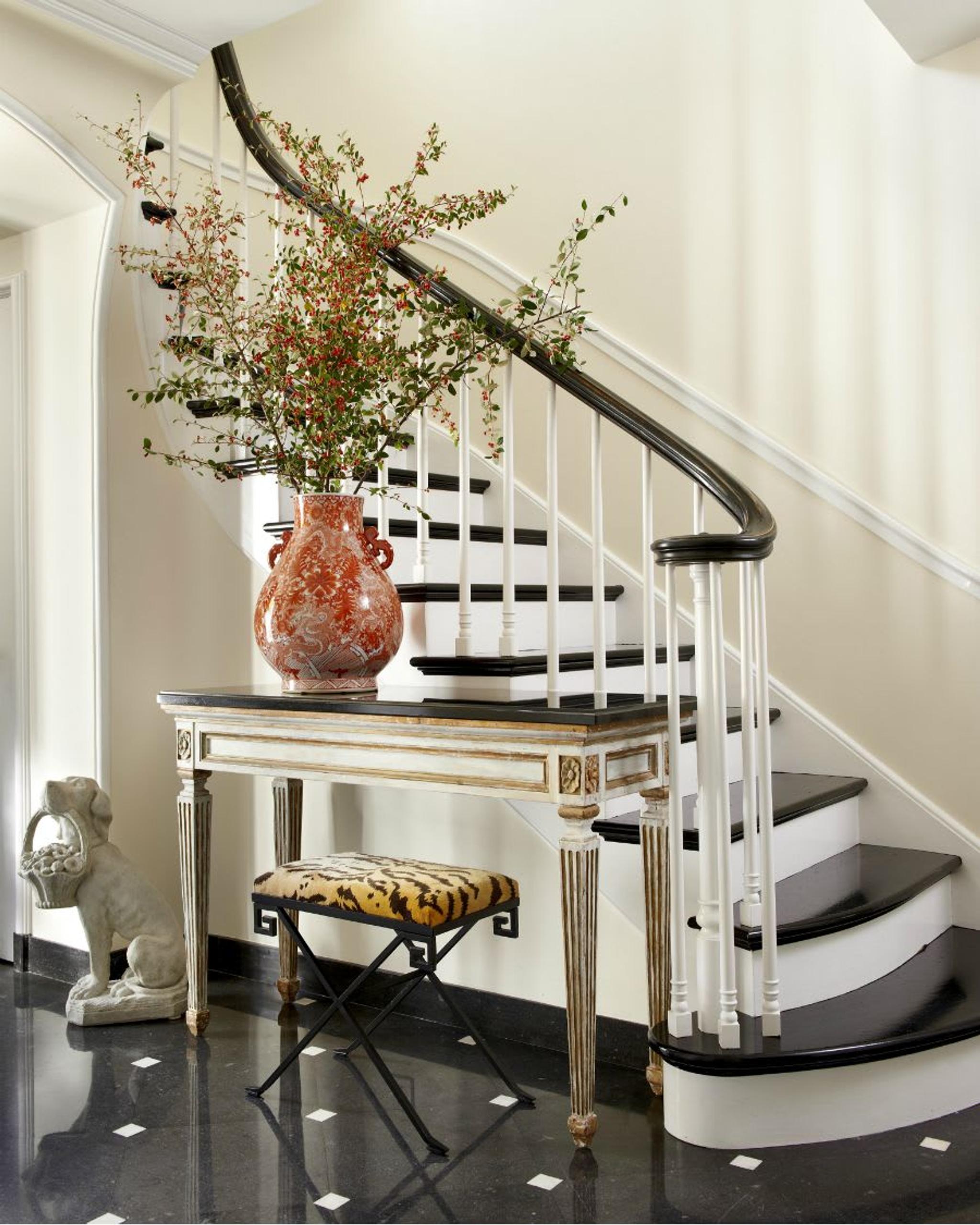 Pasillo bellamente decorado que conduce a la elegante escalera en blanco y negro.