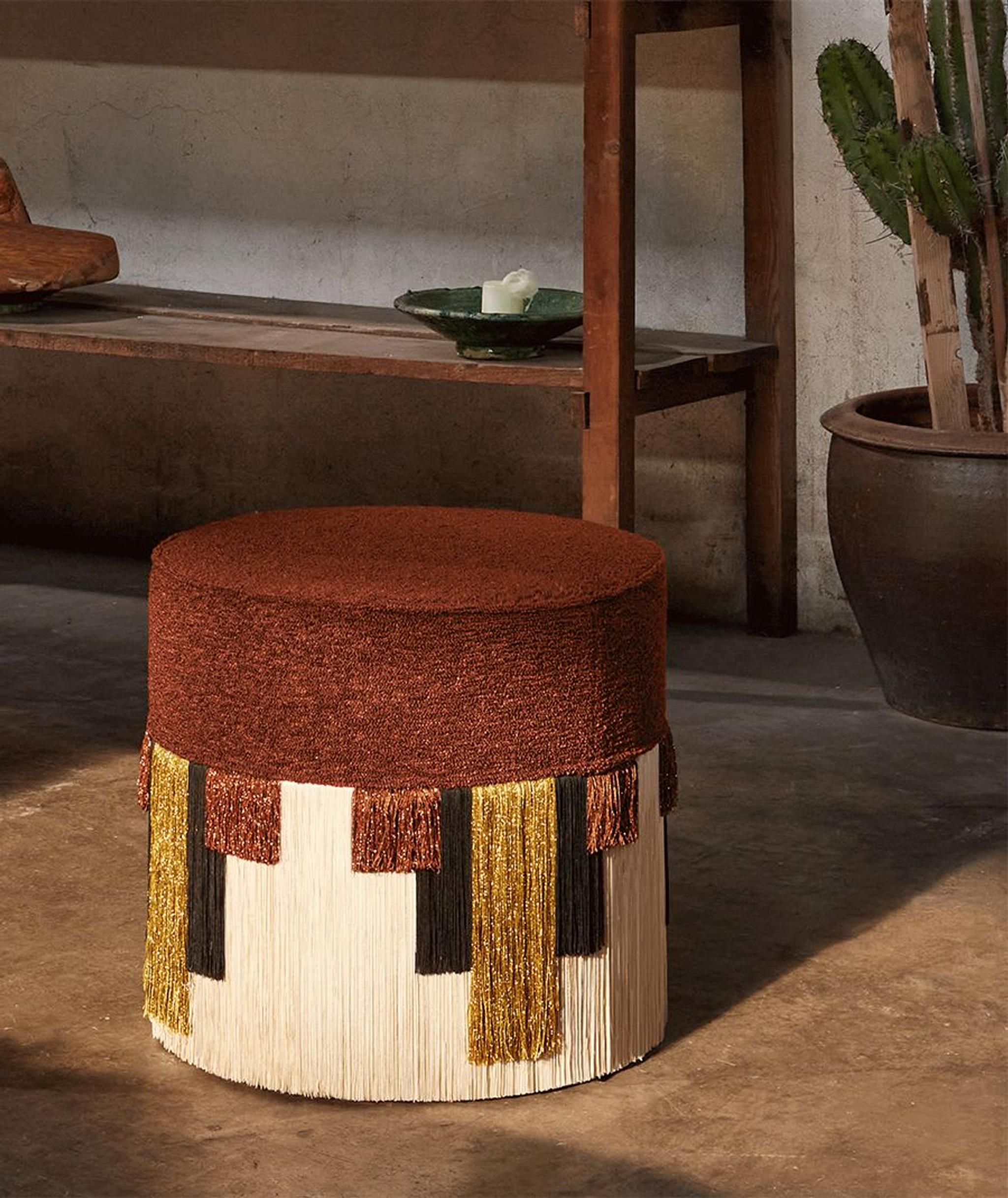 L'un des nombreux superbes accessoires de Lorenza Bozzoli, présentant un siège rembourré brun terreux, complété par une jupe à franges à motifs géométriques en viscose et lurex.