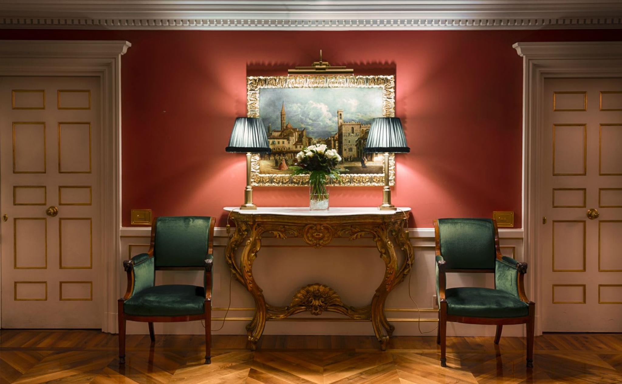 Baroque console, antique table lamps and beautiful Biedermeier armchairs lined with precious dark green velvet.