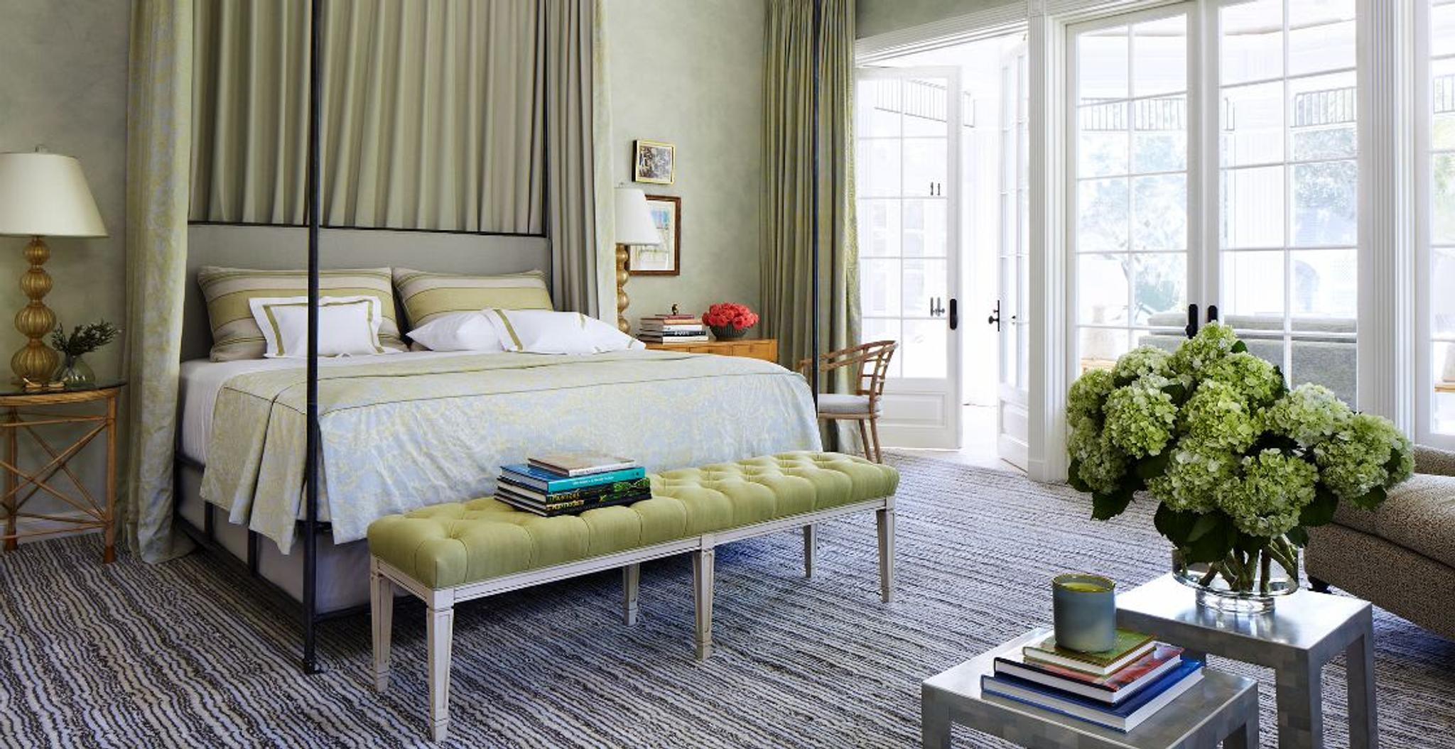 Una gruesa alfombra tejida a mano parece dibujada a rayas, mientras que una cama con dosel está equipada con colgaduras Fortuny.