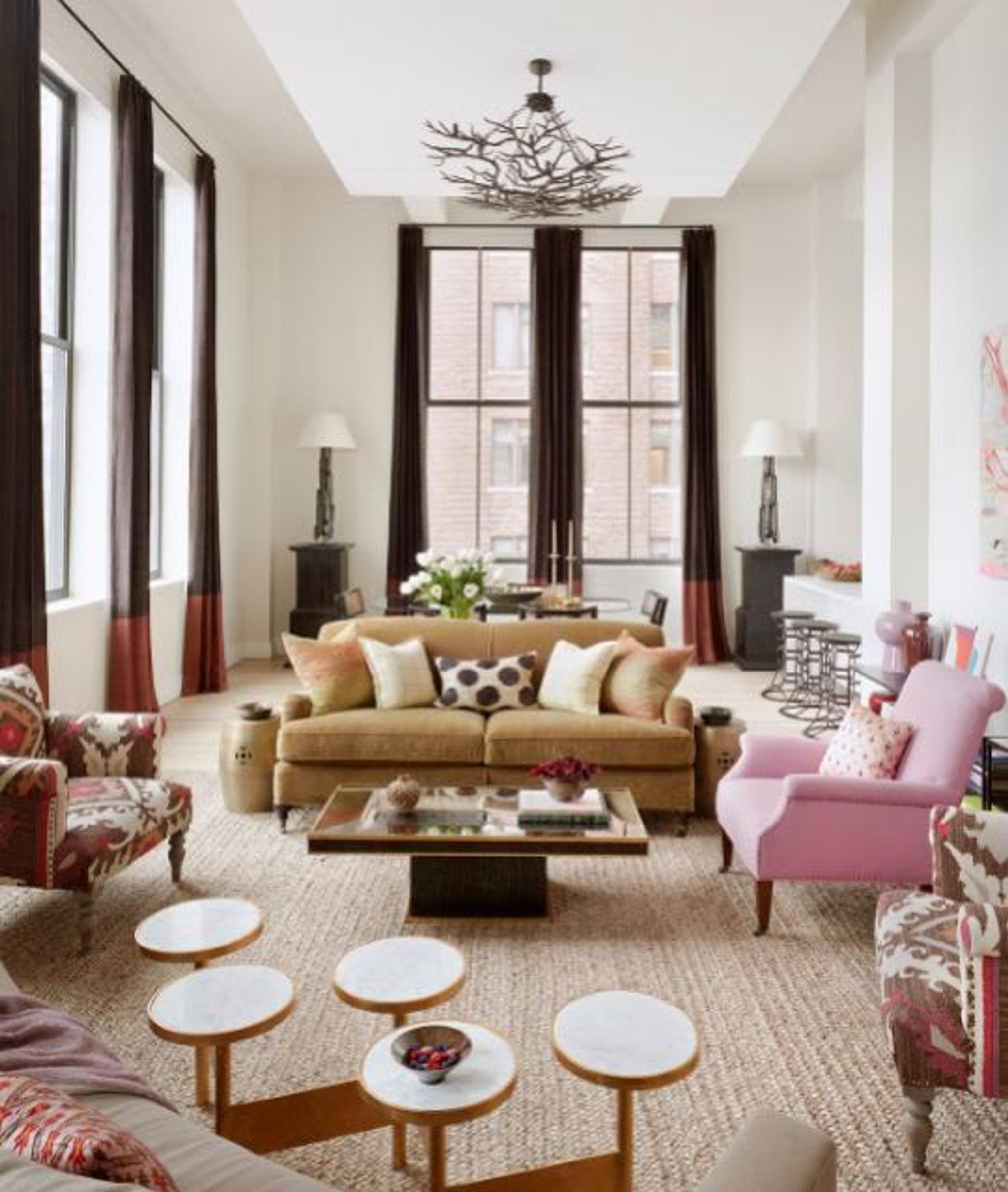 Un loft avec des plafonds à double hauteur utilisant l'emplacement des meubles pour créer une "pièce dans la pièce" pour la conversation, l'utilité et l'intérêt visuel.