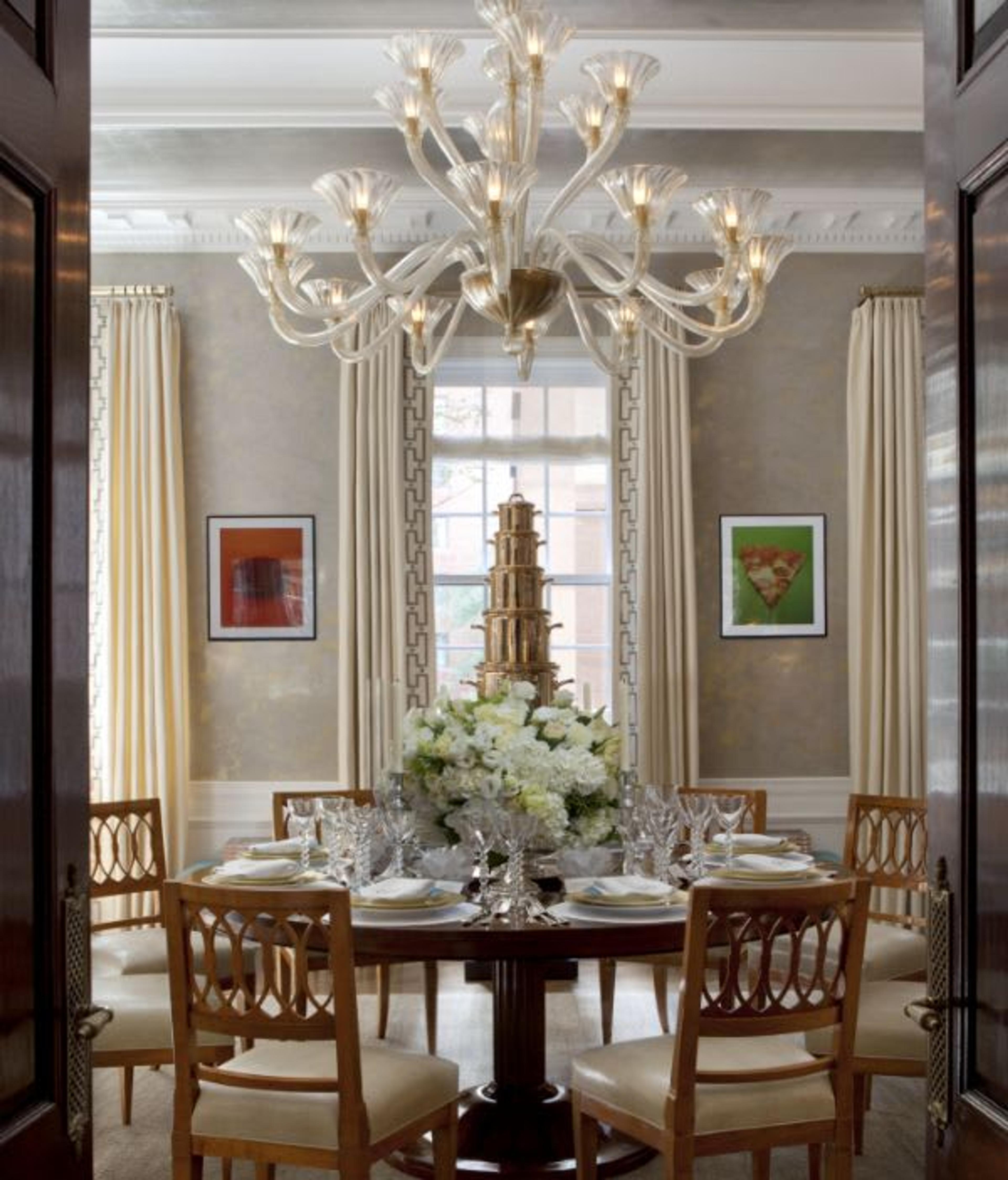 View of Kips Bay property dining table featuring a round mahogany table and a splendid glass chandelier.