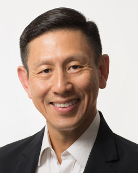 Smiling East Asian man in a black suit.