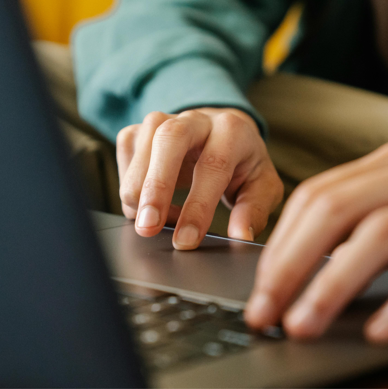 Hands using a laptop keyboard and trackpad.