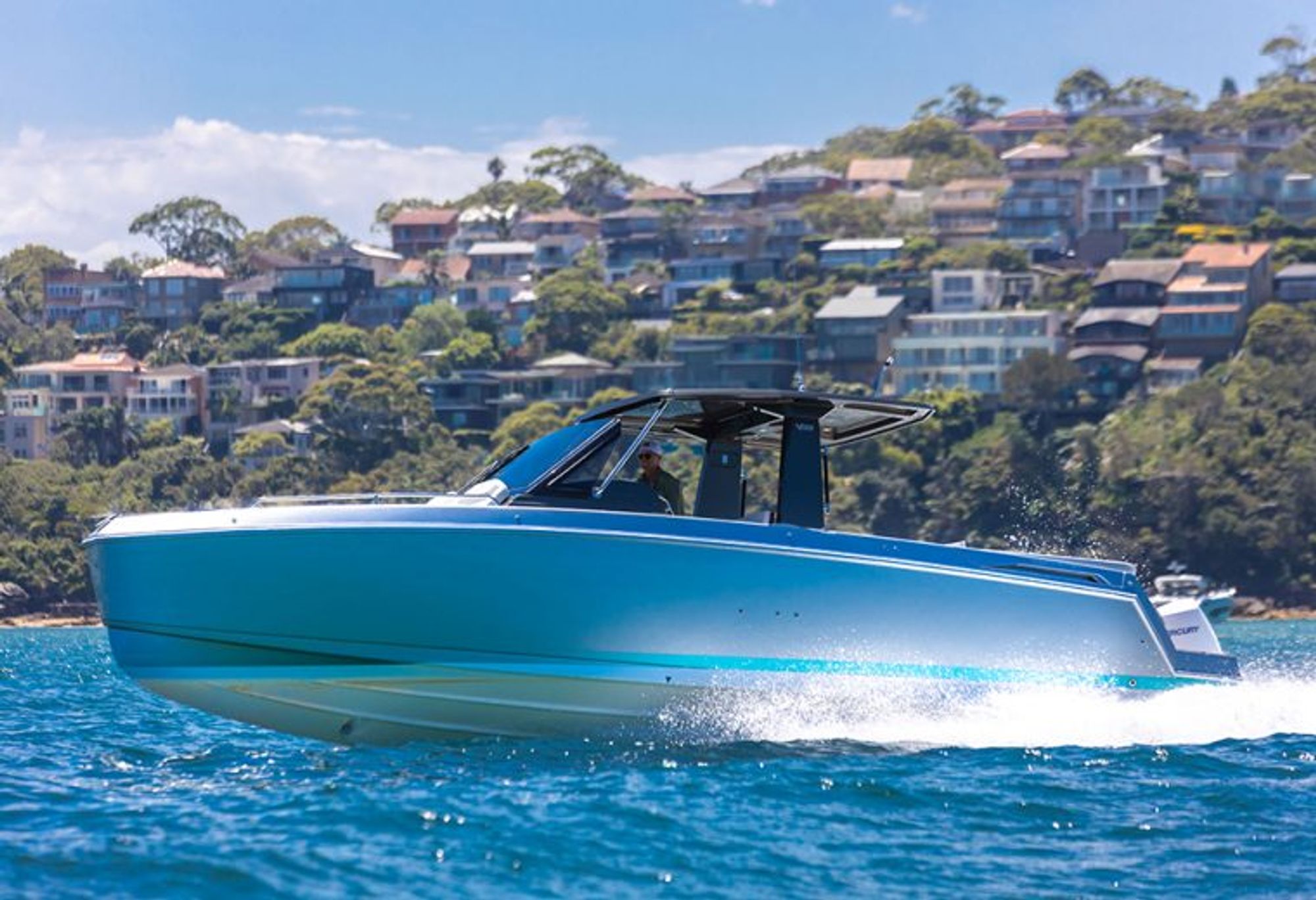 Schaefer V33 at speed on Sydney Harbour with waterfront homes behind