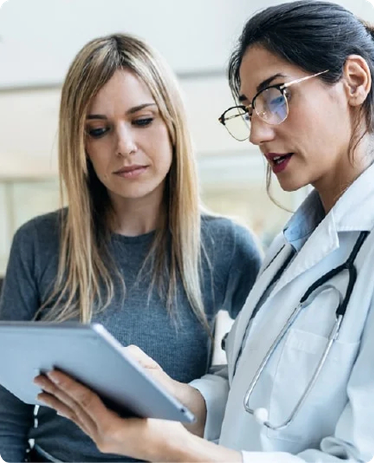 Two healthcare workers reviewing information on a tablet.