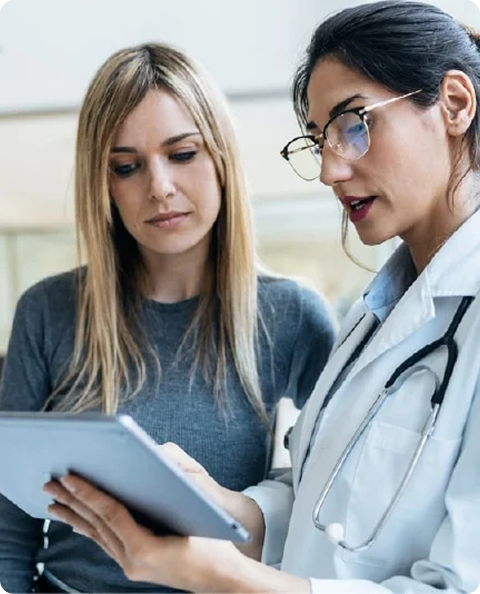 Two healthcare workers reviewing information on a tablet.