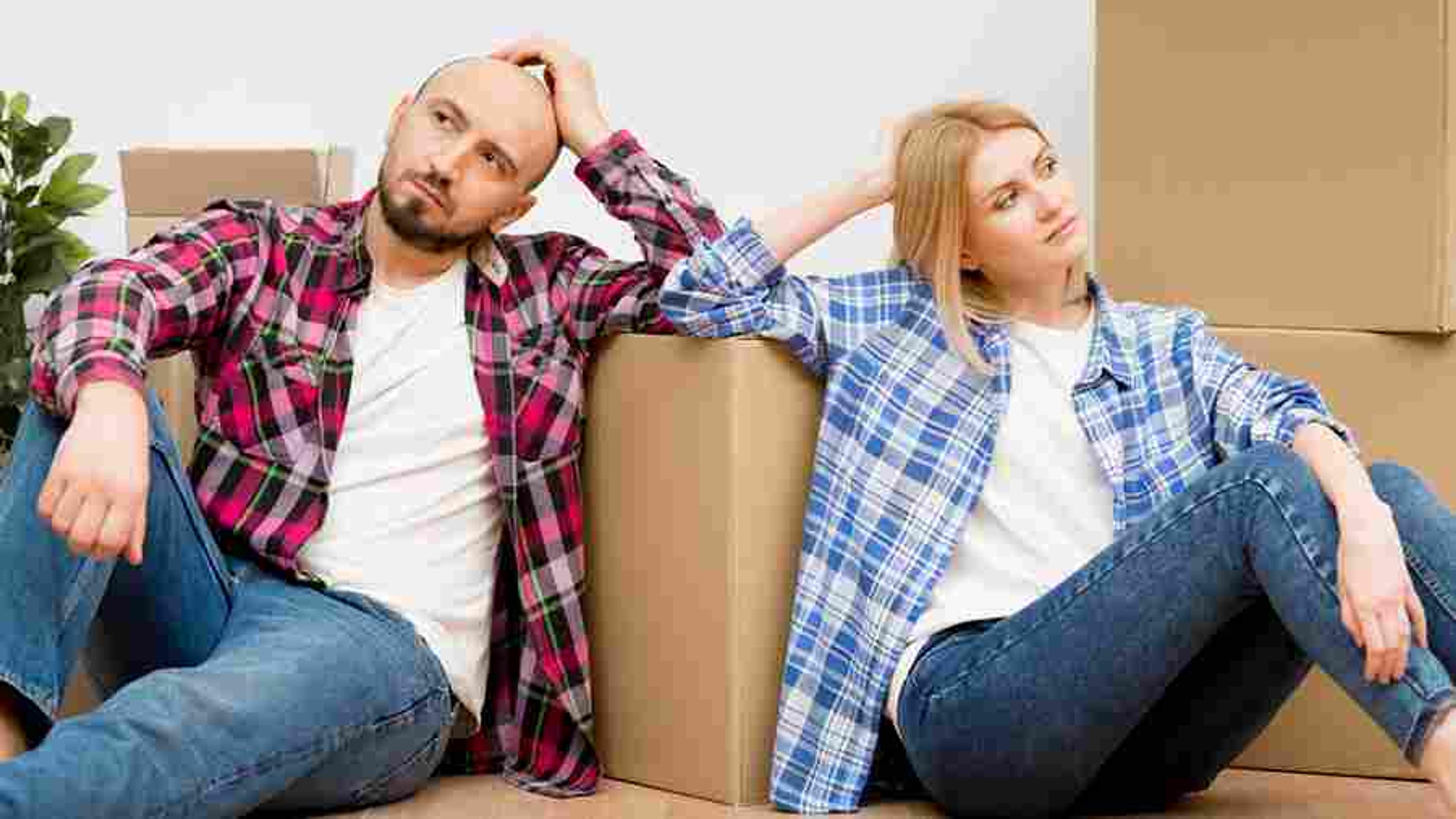Frustrated couple surrounded by moving boxes, navigating warranty claim challenges.
