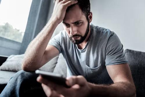 Frustrated customer reading a generic AI support reply on his phone after a warranty claim goes wrong
