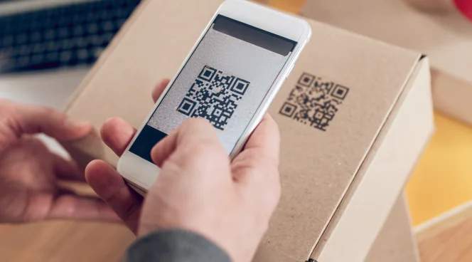 Eine Person, die mit einem Smartphone einen QR Code auf einer Verpackung scannt.
