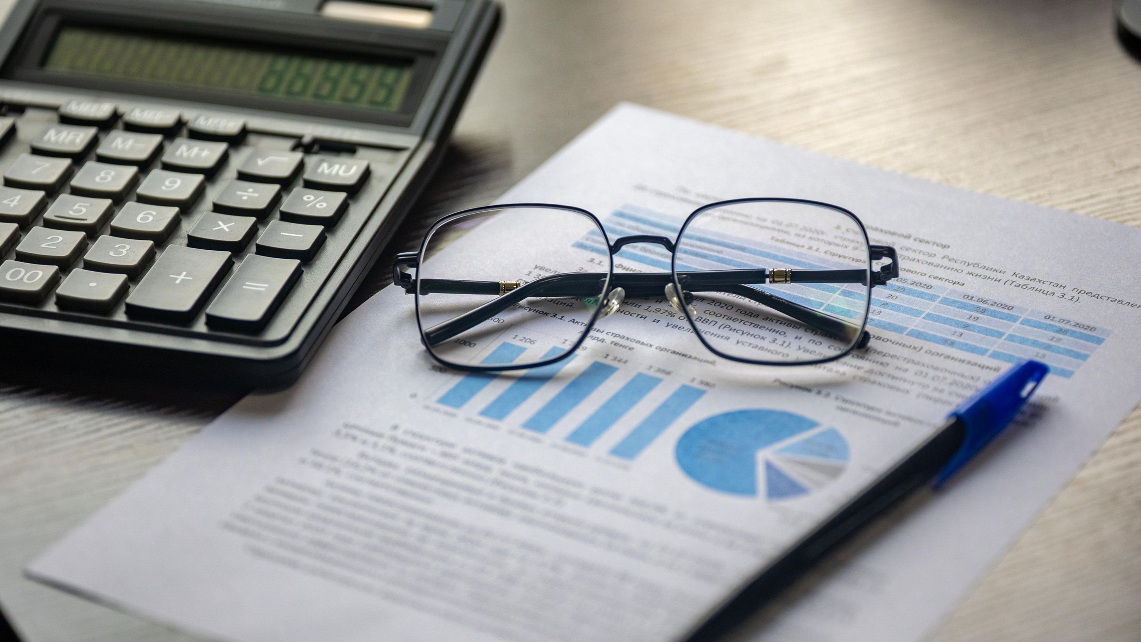Calculadora, gafas y documento financiero con gráficos sobre una mesa