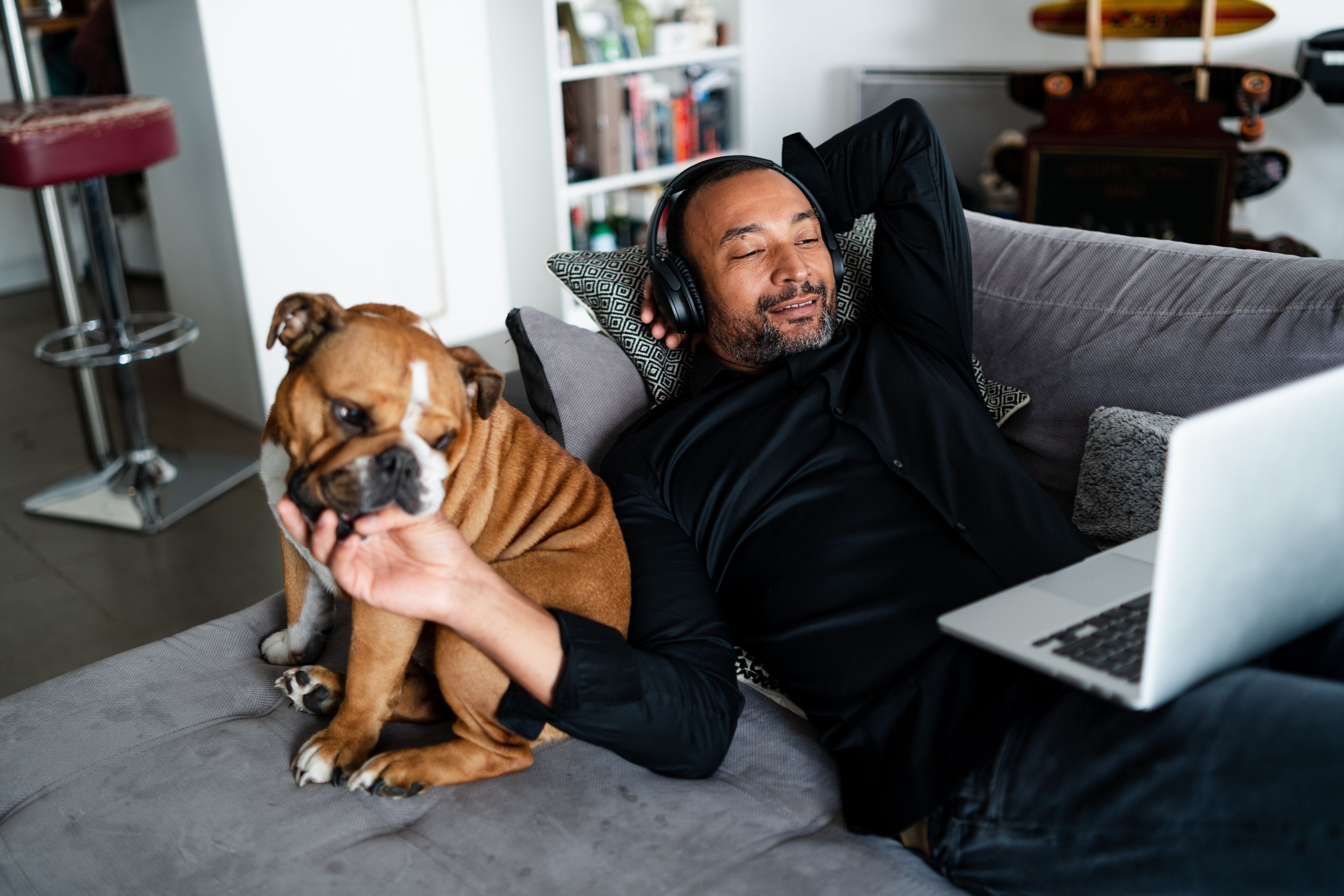Uomo di 40 anni che si rilassa sul divano e guarda un film accanto al suo bulldog
