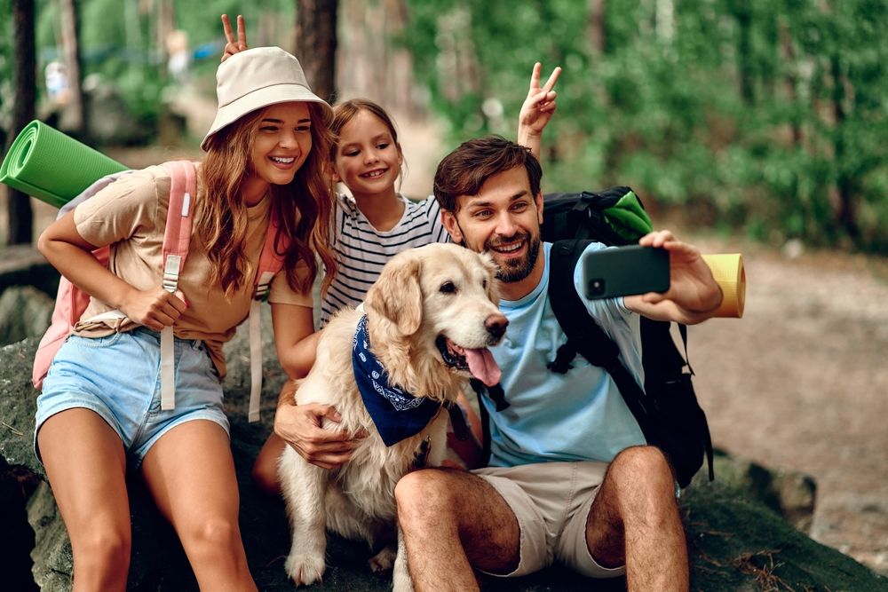 famiglia si fa selfie con il proprio cane durante una passeggiata in un bosco