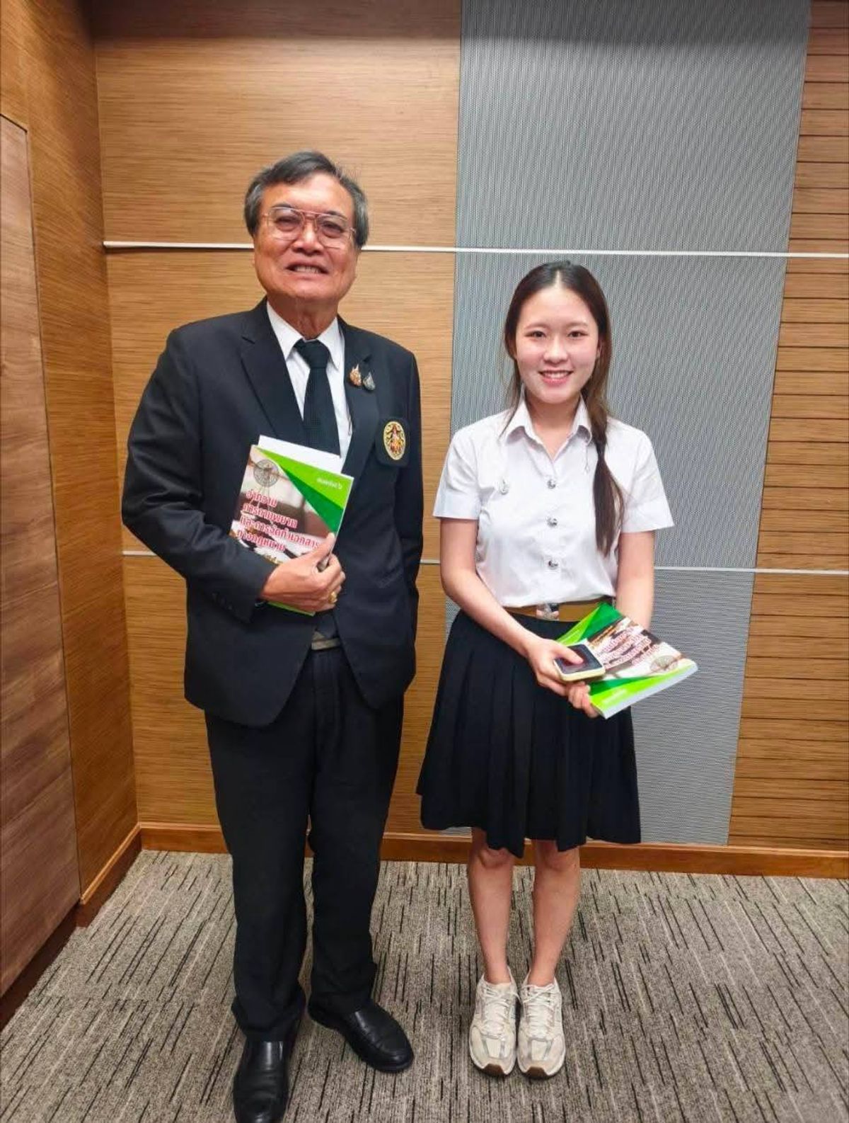 法曹協會秘書長 Thawal Ruyaporn 博士與中文實習生合影，手持協會致贈的書籍