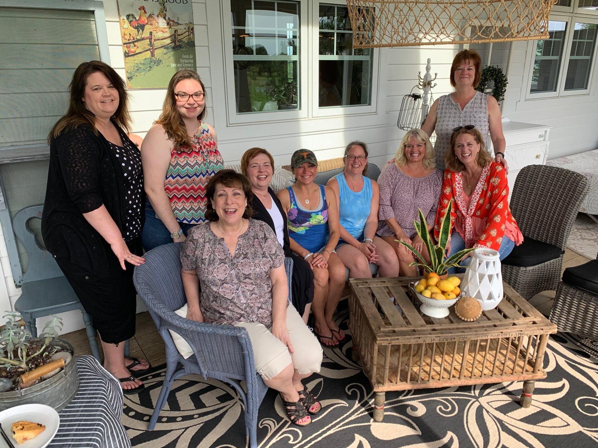 A group of team members gathers on a furnished patio for a staff get-together