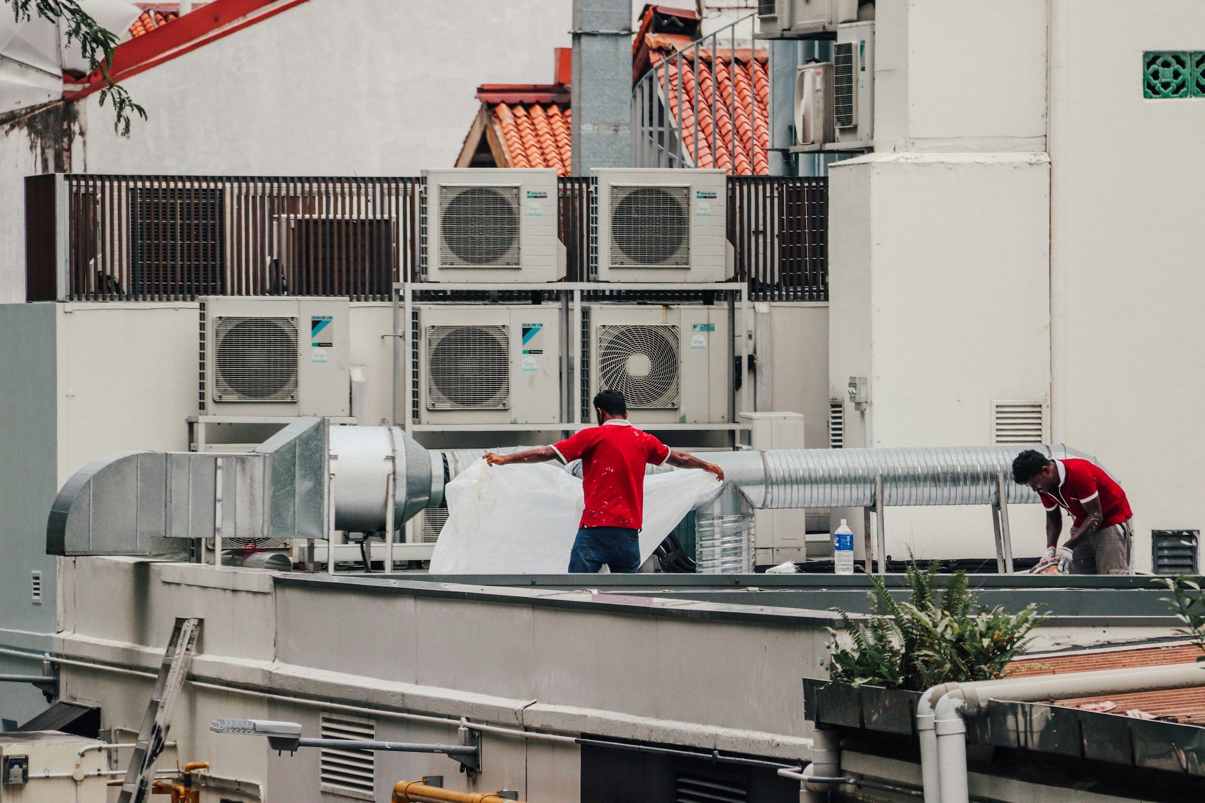 Two engineers working on a roof lined with air conditioning units