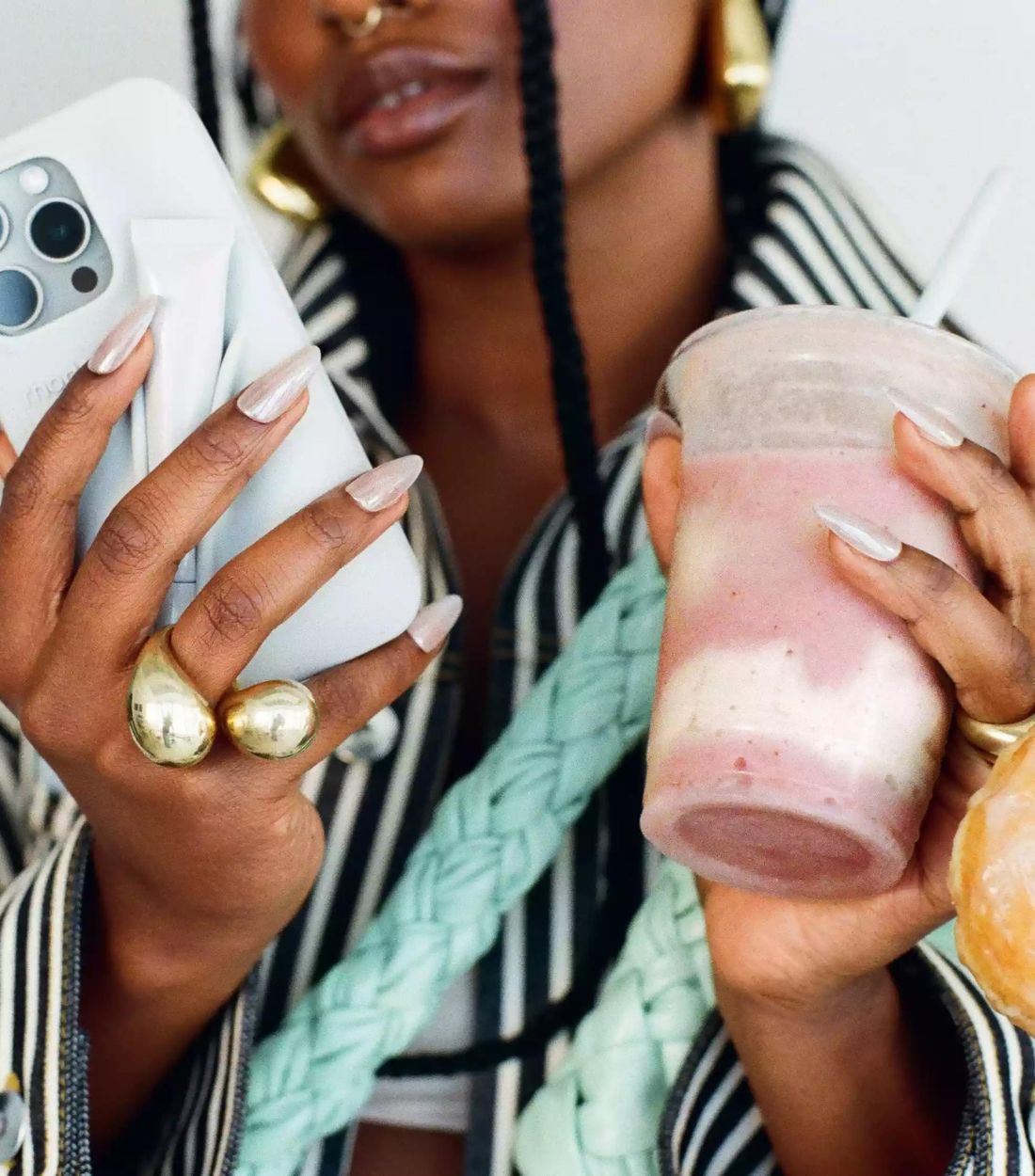 Girl holding a phone, a smoothie and a doughnut