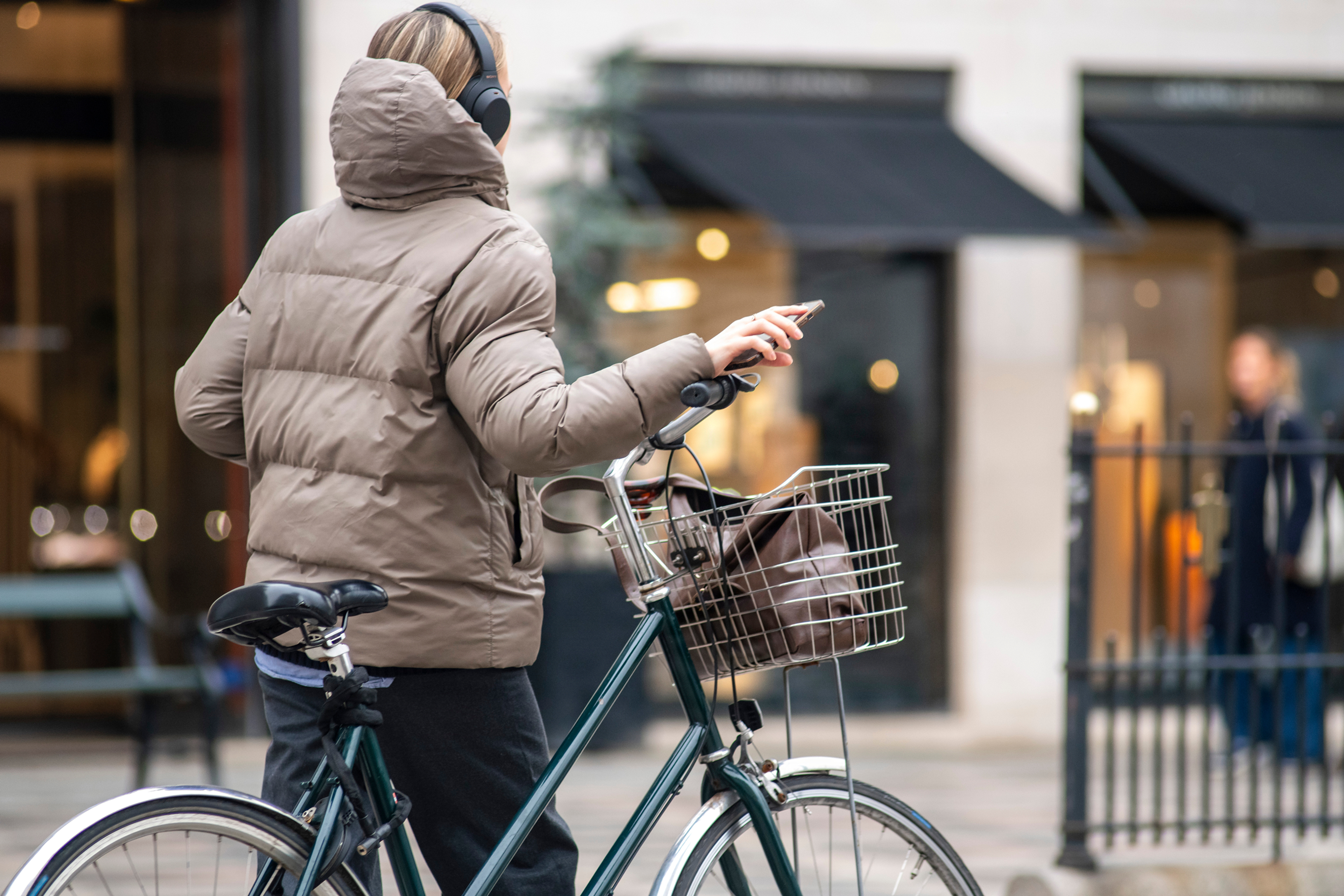 Dansk kvinde lytter til musik gående med cykel 