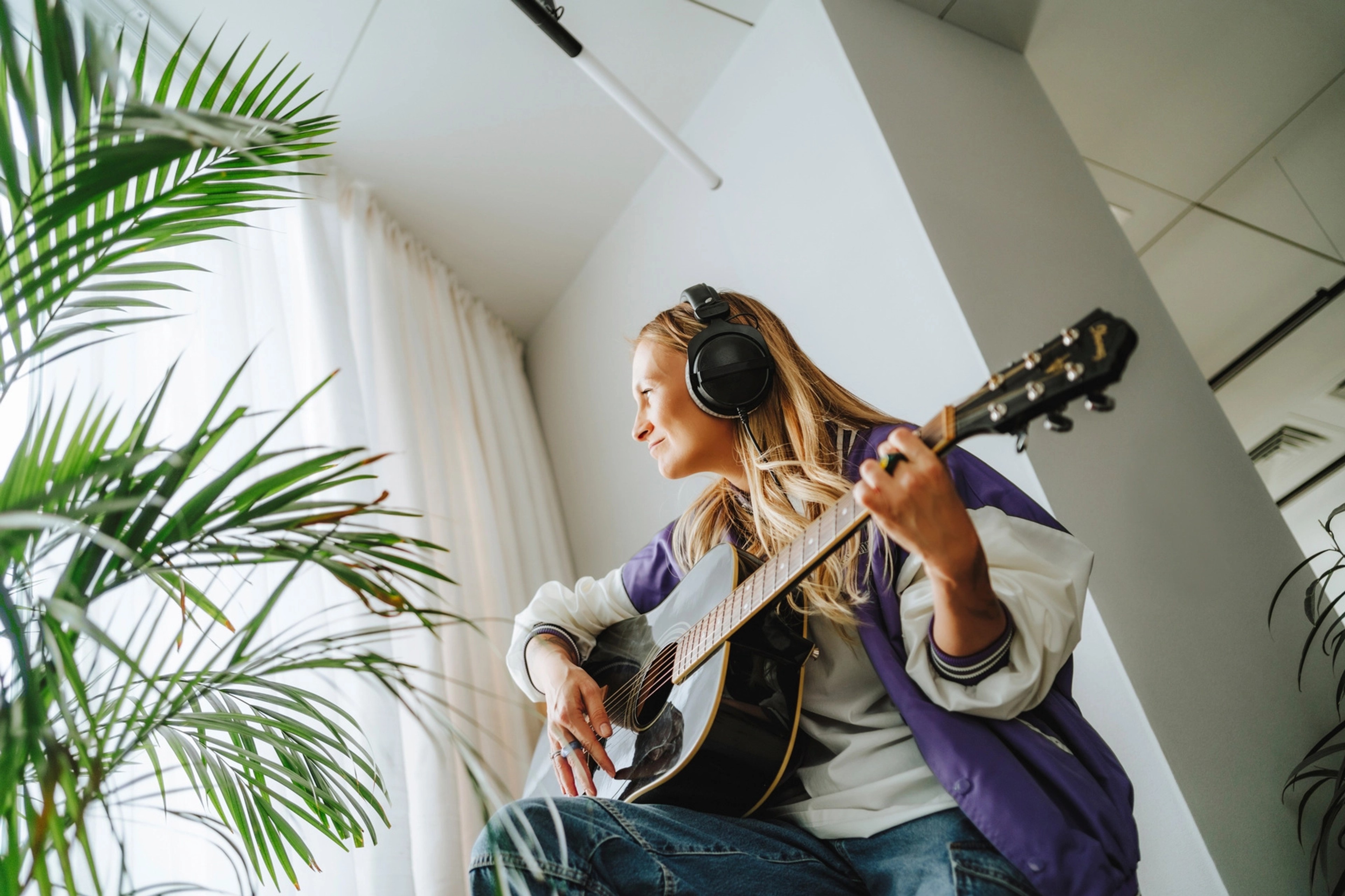 Kvinde spiller guitar i vindueskarm
