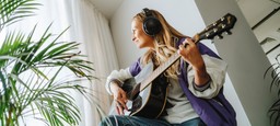 Kvinde spiller guitar i vindueskarm