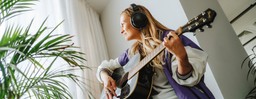 Kvinde spiller guitar i vindueskarm