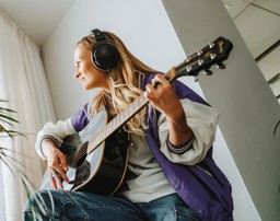 Kvinde spiller guitar i vindueskarm