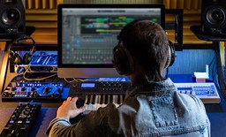 Person foran computer og keyboard indspiller musik