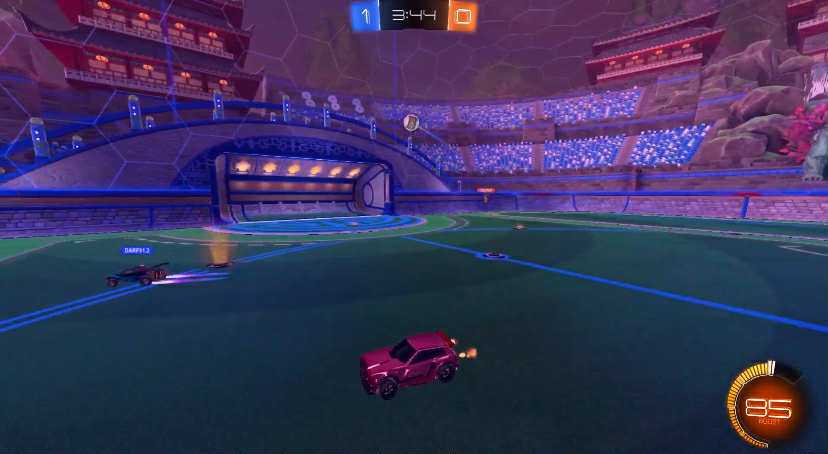 A red car on a soccar pitch.