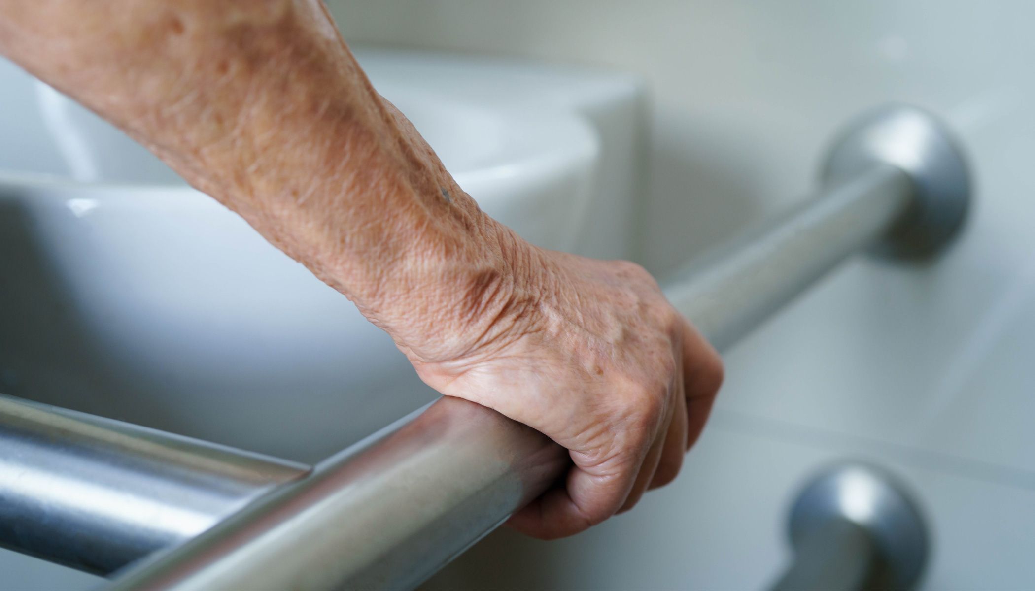 An older person holding a rail in an assisted living home