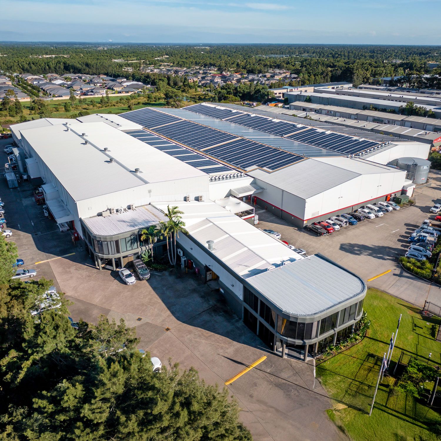 An aerial overview of a factory with solar panels on the roof