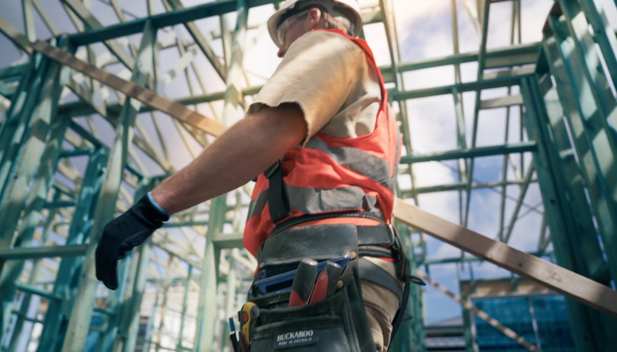 A carpenter walking past a house frame built in MGP10H2