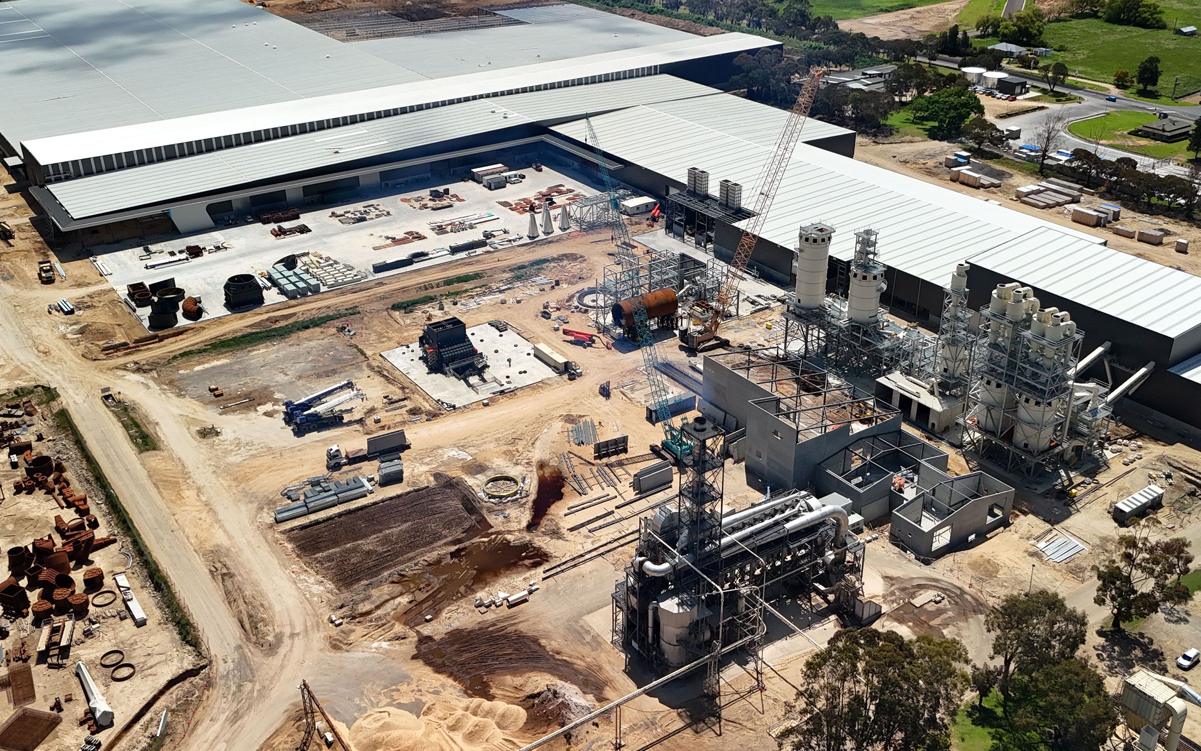 A factory with stacks of particleboard panels in the foreground and a large particleboard fanned cooling rack in the background
