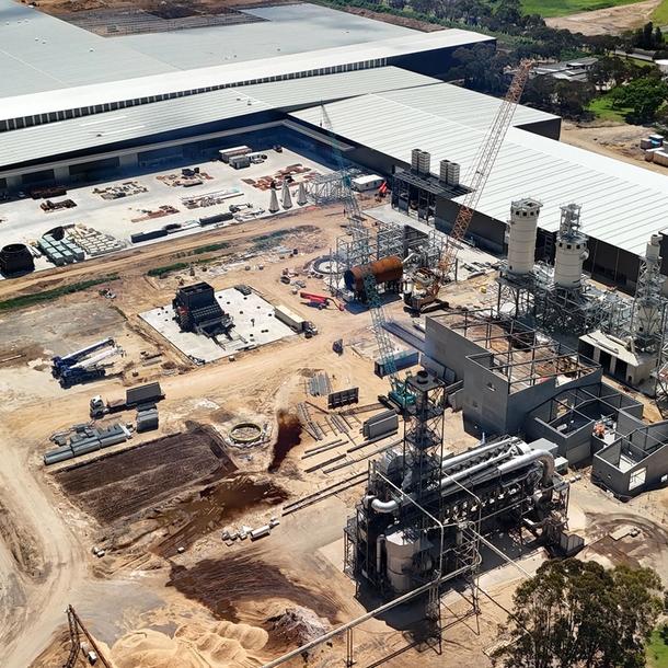 A factory with stacks of particleboard panels in the foreground and a large particleboard fanned cooling rack in the background