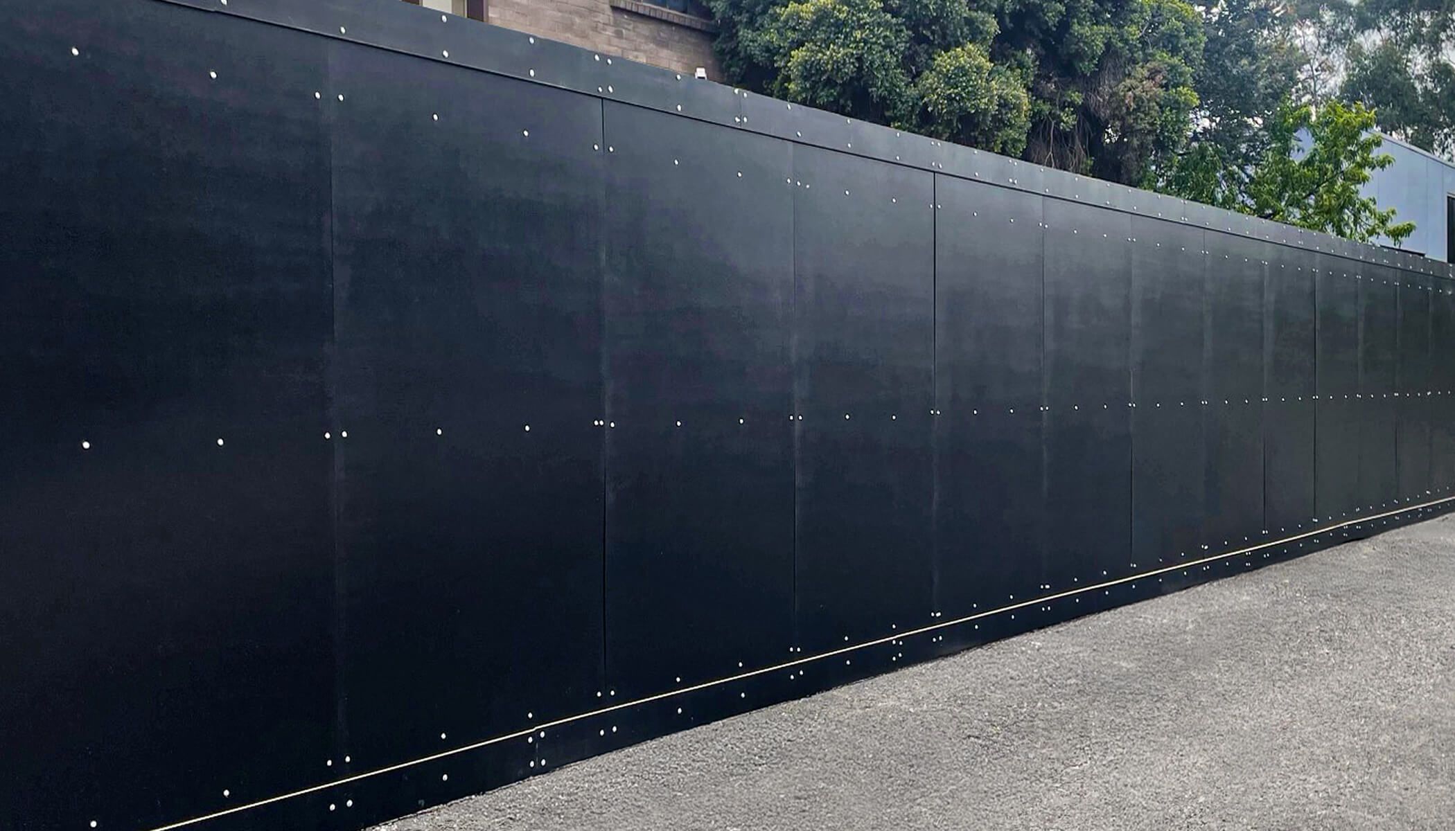 Black outdoor hoarding displayed in an outdoor setting.