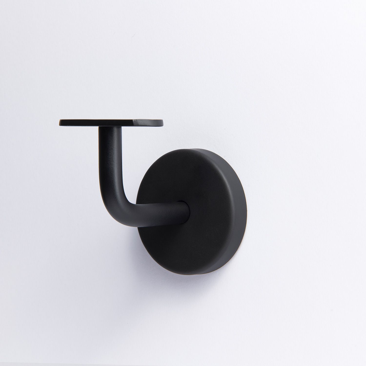 A handrail bracket with a round base plate, a curved support arm, and a flat mounting plate on top in Black 70mm 43mm