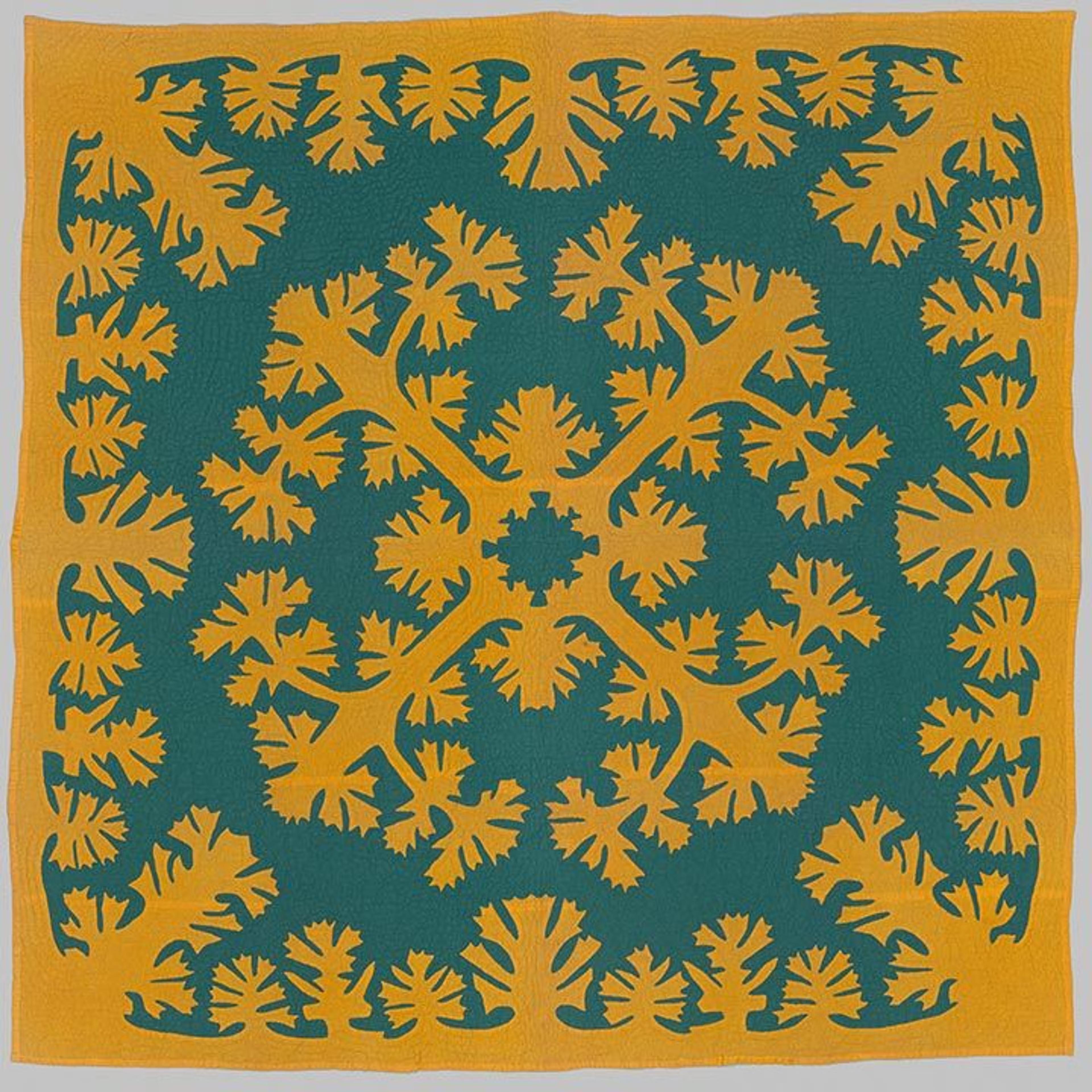 A teal quilt with yellow fringe and a symmetrical yellow design in its center. Both the center and edge designs feature complex, ornate, flower blossom-like patterns that extend identically into all four corners of the quilt.